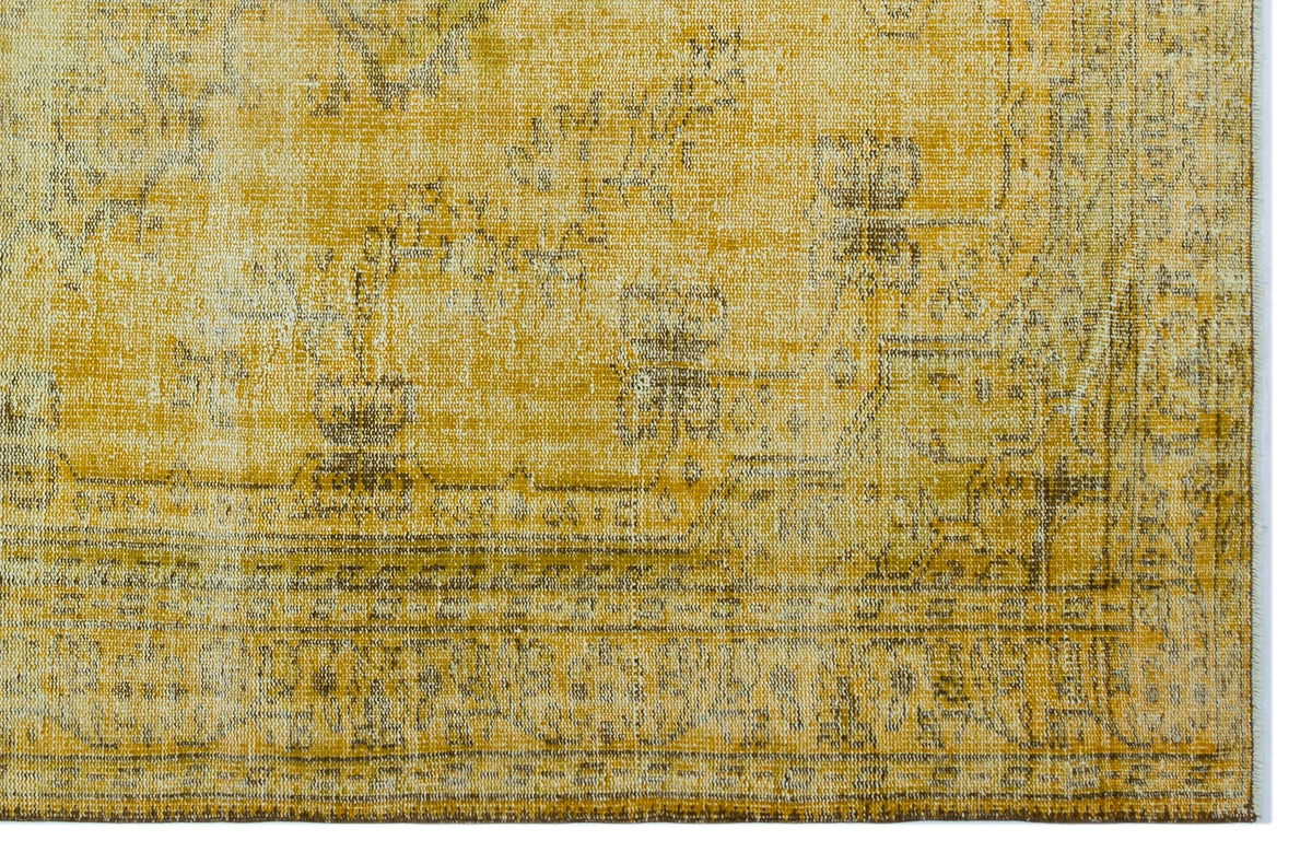 Mustard yellow and brown distressed rug with a faded traditional medallion pattern on a white background.
