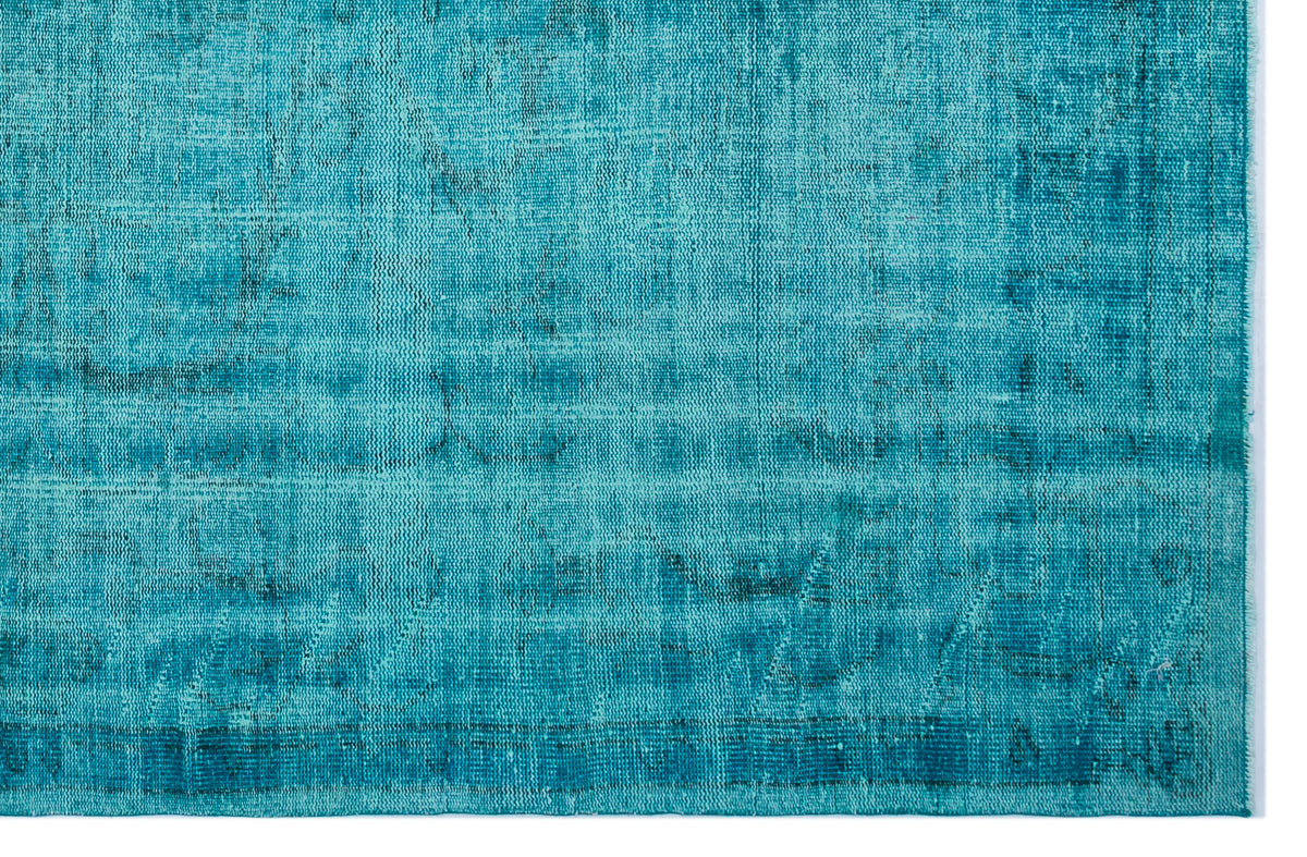 Teal distressed vintage-style rug with a faded, textured pattern and a visible woven border.
