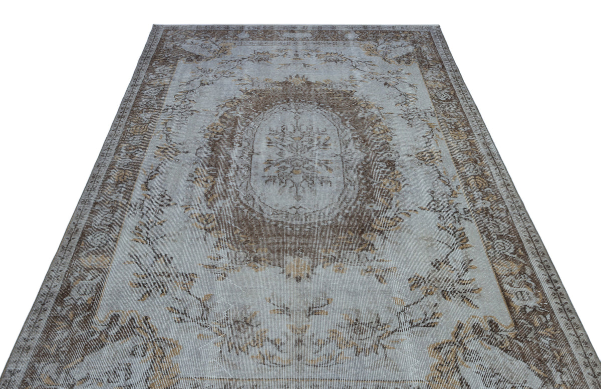 Light blue and brown distressed rug with a central floral medallion and ornate border pattern.