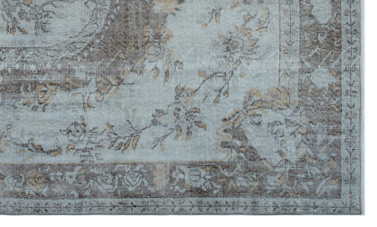 Light blue and brown rug with a distressed floral medallion pattern and a decorative border.