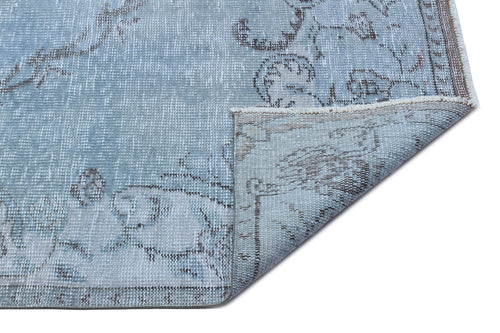 Load image 1 in gallery view. Light blue distressed rug with a faded floral pattern and a folded corner revealing the woven backing.