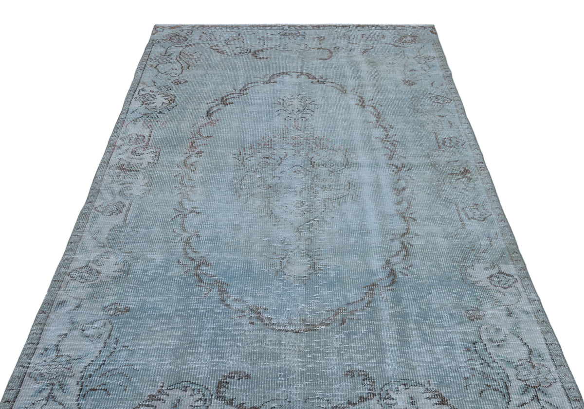 Light blue distressed rug with a faded central medallion and floral border pattern on a white background.