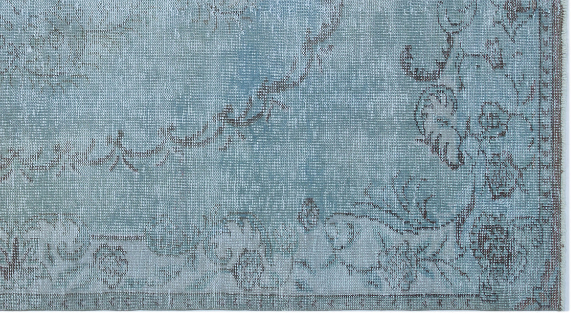 Light blue distressed rug with a faded brown floral medallion pattern on a white background.