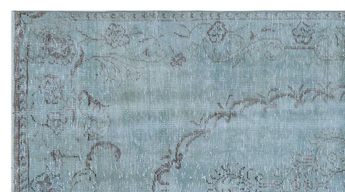 Light blue distressed rug with a faded brown floral pattern and a traditional border.