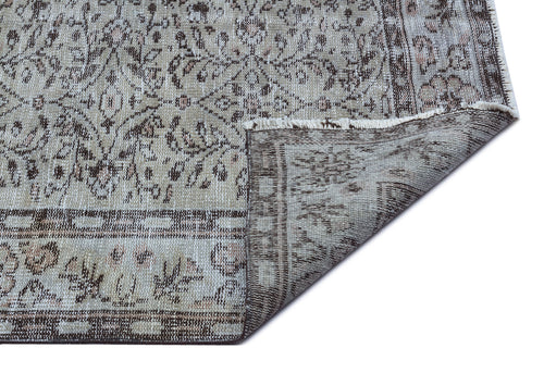 Load image 1 in gallery view. Beige and brown distressed traditional rug with a floral medallion pattern, shown with a corner folded over.