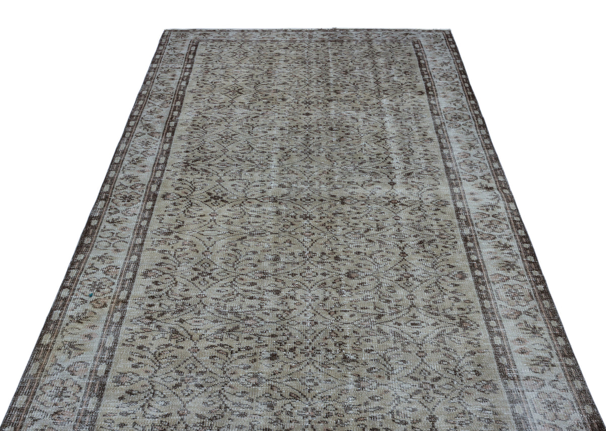 Beige and brown vintage-style rug with a distressed floral medallion pattern and a decorative border.