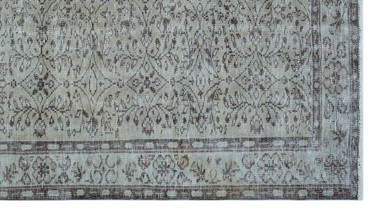 Beige and brown distressed vintage-style rug with a traditional floral medallion pattern and a geometric border.