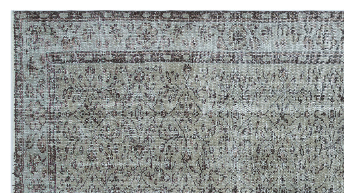 Distressed taupe and grey rug with a traditional floral medallion pattern and a geometric border.