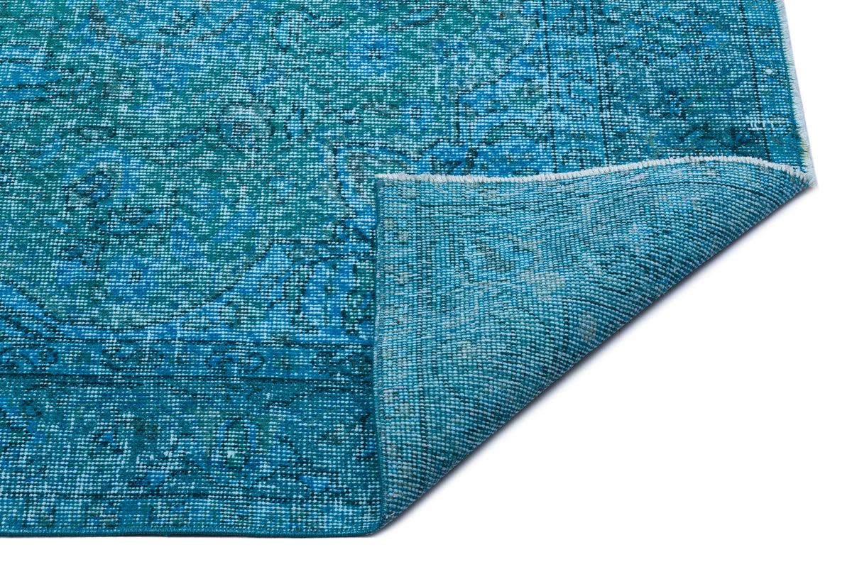 Teal and blue distressed medallion rug with a folded corner revealing the woven backing on a white background.