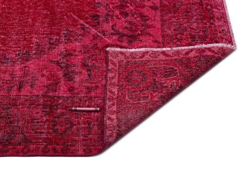 Load image 1 in gallery view. Deep red distressed rug with a dark floral medallion pattern and a folded corner, isolated on a white background.