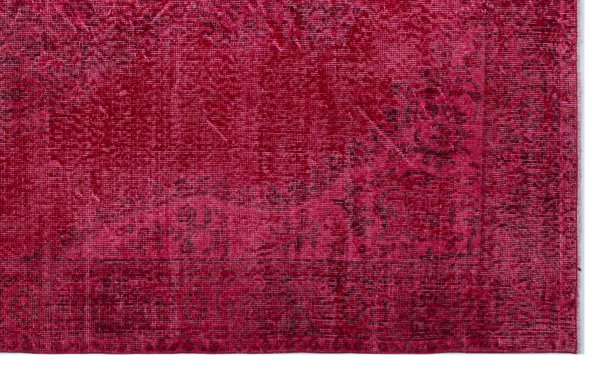 Magenta distressed rug with a faded traditional floral medallion pattern and a dark border.