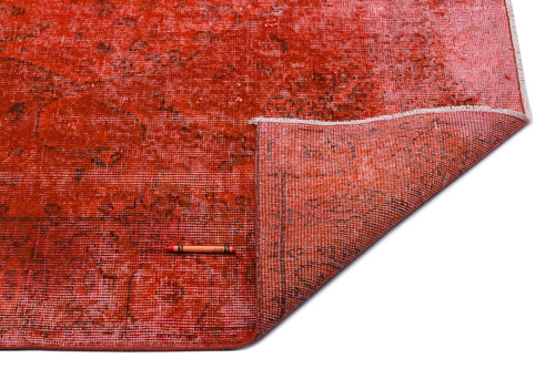 Load image 1 in gallery view. Distressed red and pink vintage-style rug with a faded floral medallion pattern, shown with a corner folded over.