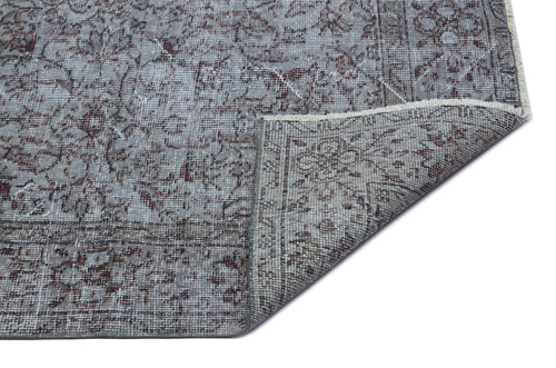 Load image 1 in gallery view. Grey and brown distressed traditional rug with a floral medallion pattern, shown with a corner folded over.