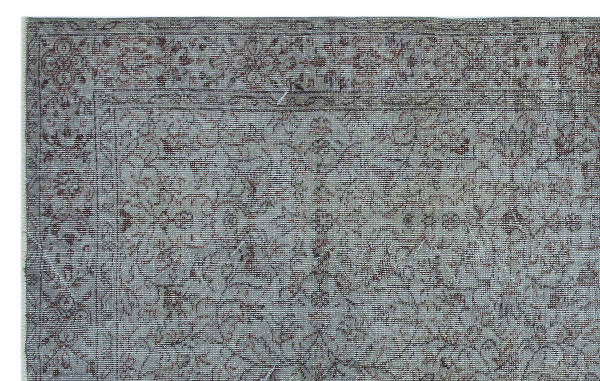 Grey and brown traditional rug with a distressed floral vine pattern and a decorative border.