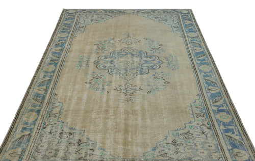 Load image 1 in gallery view. Beige and blue distressed area rug with a central floral medallion and ornate border pattern on a white background.