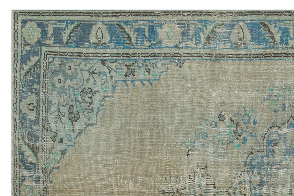 Beige and blue traditional rug with a distressed floral medallion pattern and a decorative border.