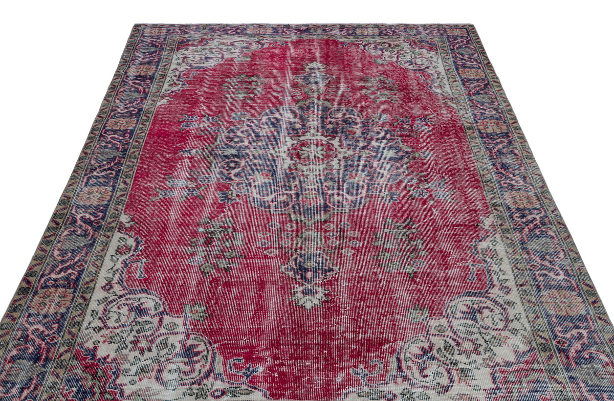Distressed red vintage-style rug with a central blue and cream floral medallion and ornate border.