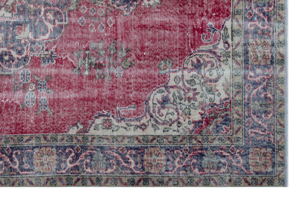 Distressed red, navy, and cream rug with a traditional floral medallion pattern and an ornate border.