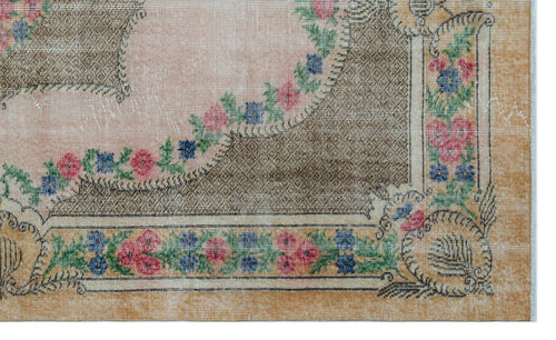 Load image 1 in gallery view. Vintage-style rug with a pink central field, tan border, and floral garland pattern in red, blue, and green.