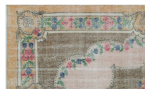 Load image 1 in gallery view. Distressed tan rug with a floral border in pink, blue, and green, featuring a central medallion design.