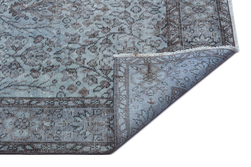 Load image 1 in gallery view. Blue and grey distressed traditional rug with a floral medallion pattern, shown with a corner folded over.