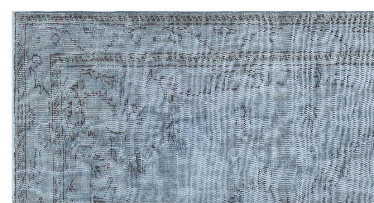 Light blue and grey distressed rug with a faded traditional floral border and central medallion pattern.