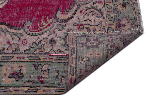 Load image 1 in gallery view. Distressed magenta, sage green, and beige vintage-style rug with a floral medallion pattern and a folded corner.
