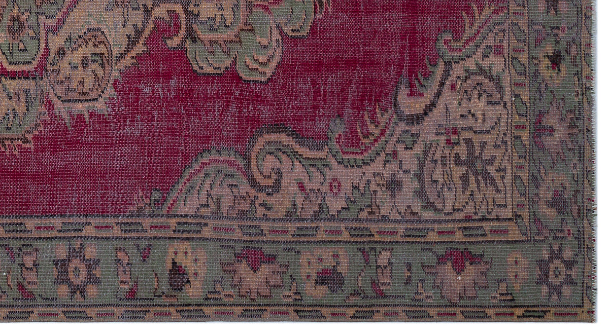Distressed crimson rug with sage green and beige ornate floral borders and a traditional medallion pattern.
