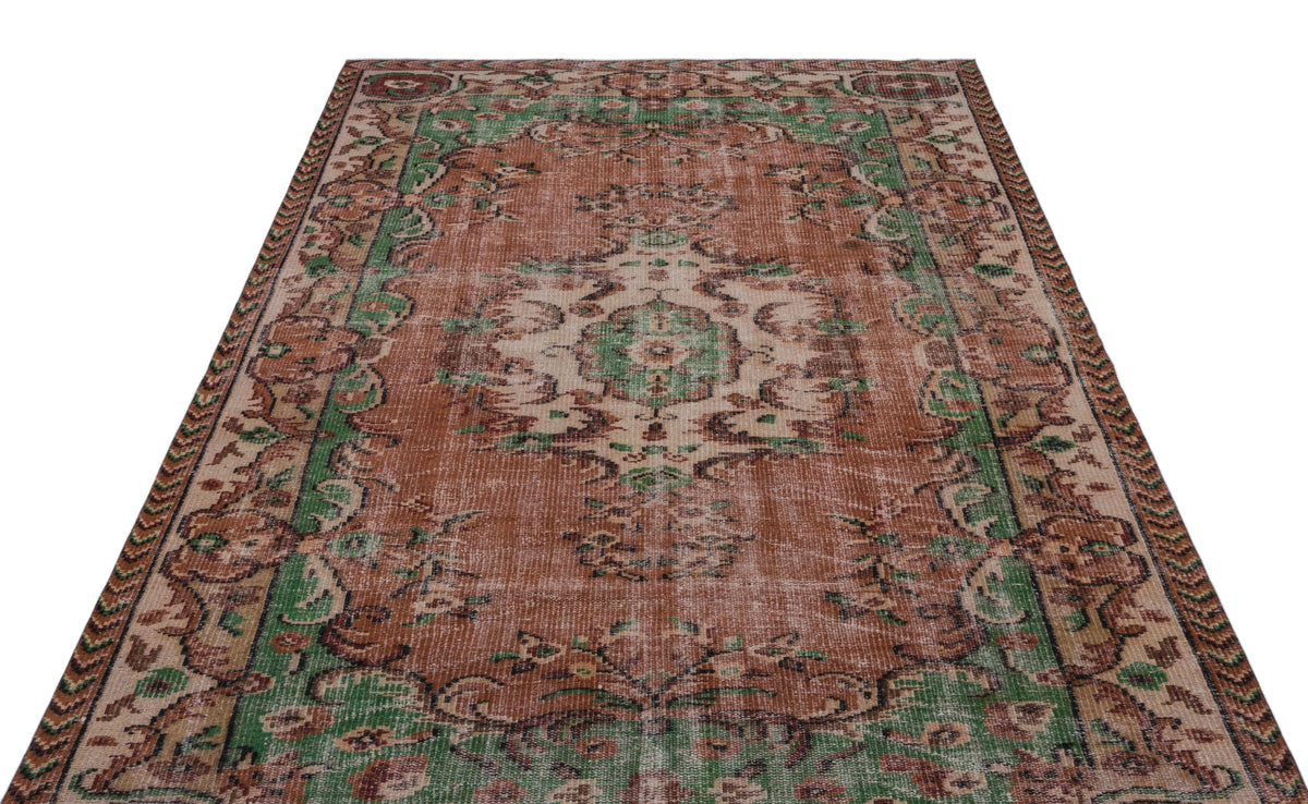 Distressed terracotta, green, and cream vintage-style rug with a central floral medallion and ornate border.