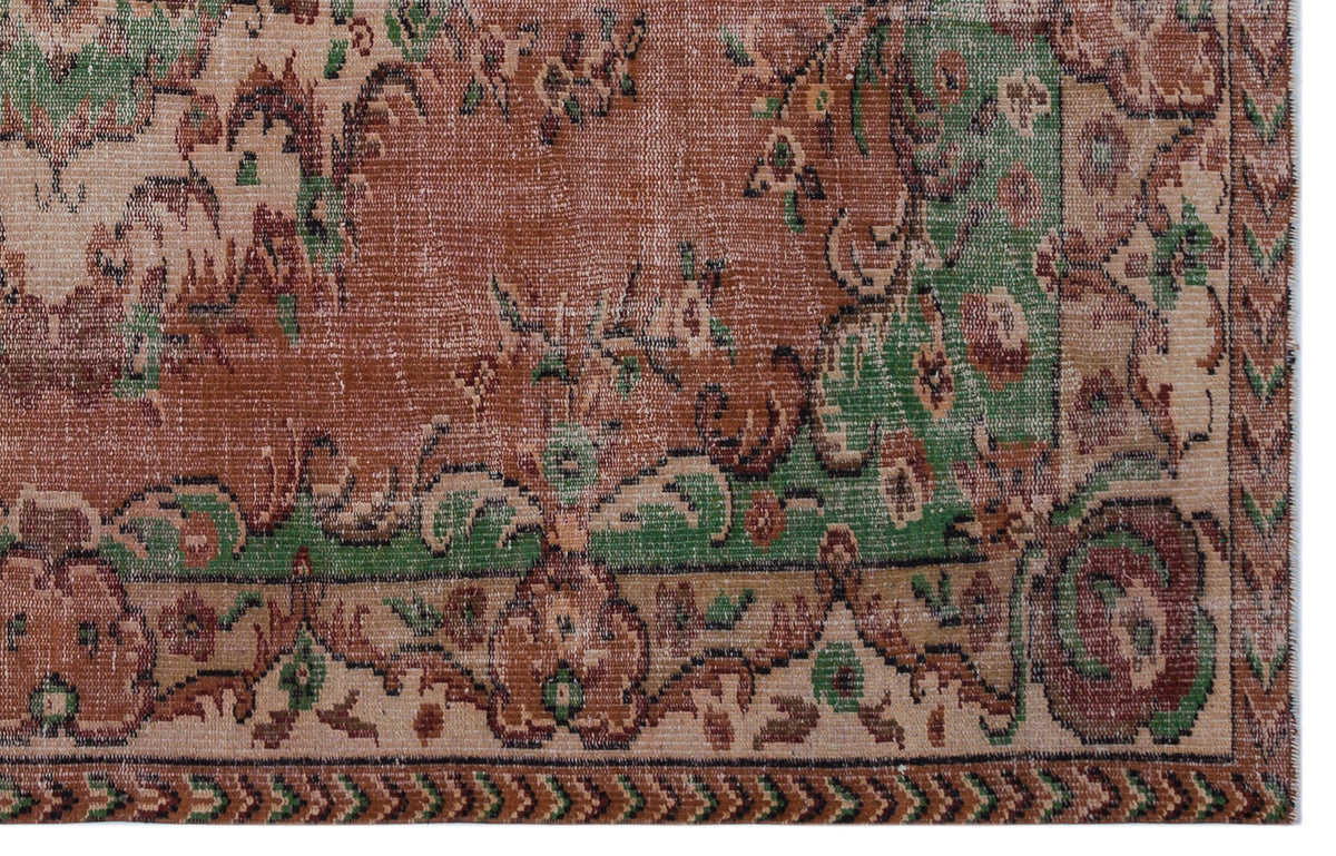 Distressed terracotta, green, and beige rug with a traditional floral medallion pattern and a geometric border.