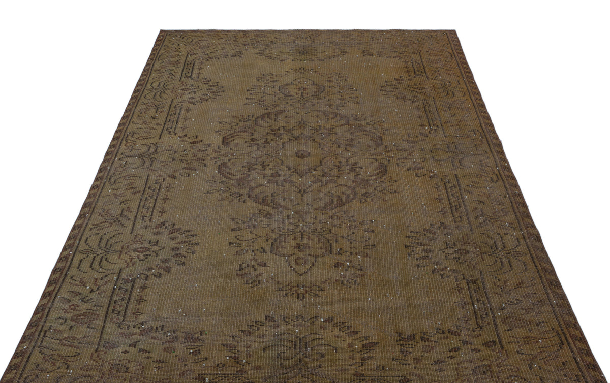 Distressed brown vintage rug with a central floral medallion and ornate border pattern on a white background.