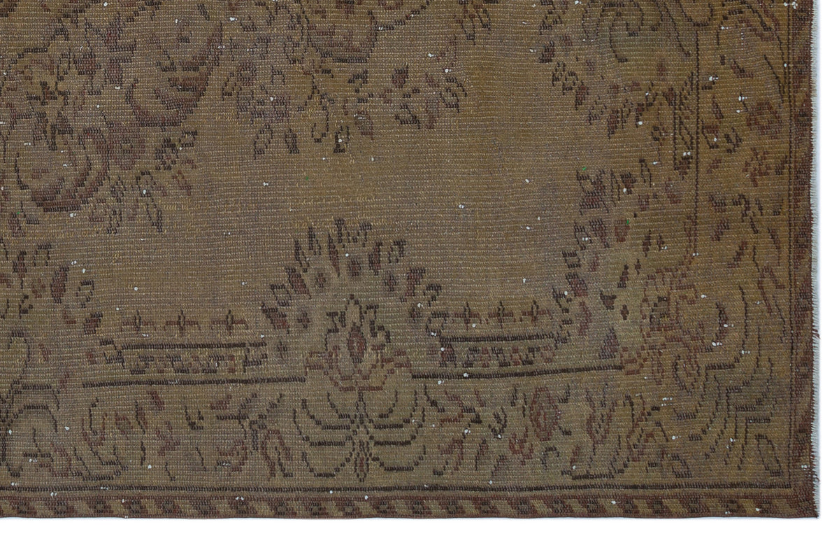Brown distressed rug with a faded traditional floral medallion pattern and a geometric border.