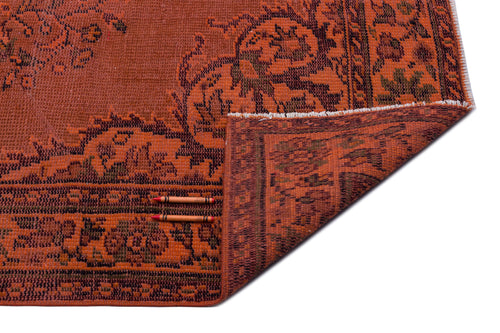 Load image 1 in gallery view. Rust-colored vintage-style rug with a dark floral border and a corner folded over, isolated on a white background.