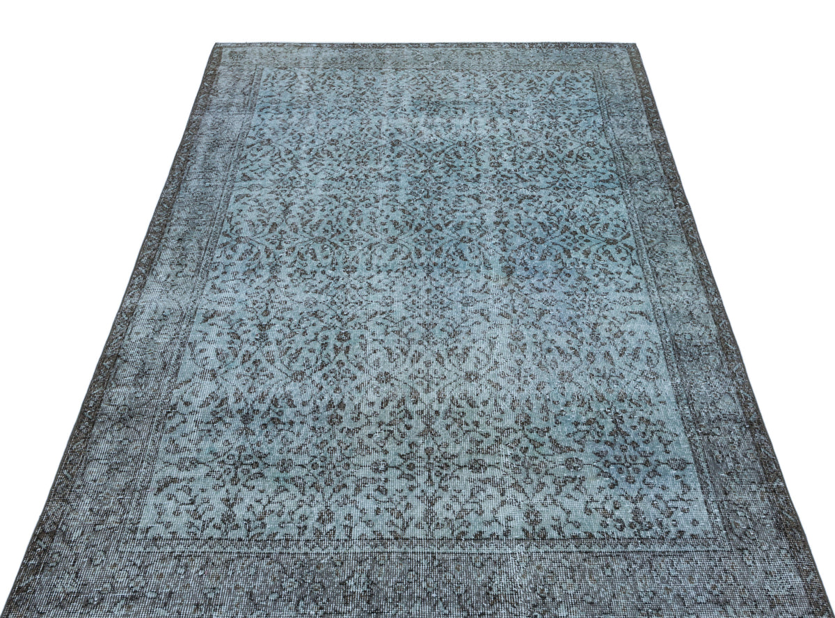 Distressed blue and charcoal grey rug with an intricate floral medallion pattern and a wide decorative border.