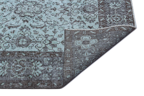 Load image 1 in gallery view. Light blue and dark brown rug with a distressed floral medallion pattern, shown with a corner folded over.