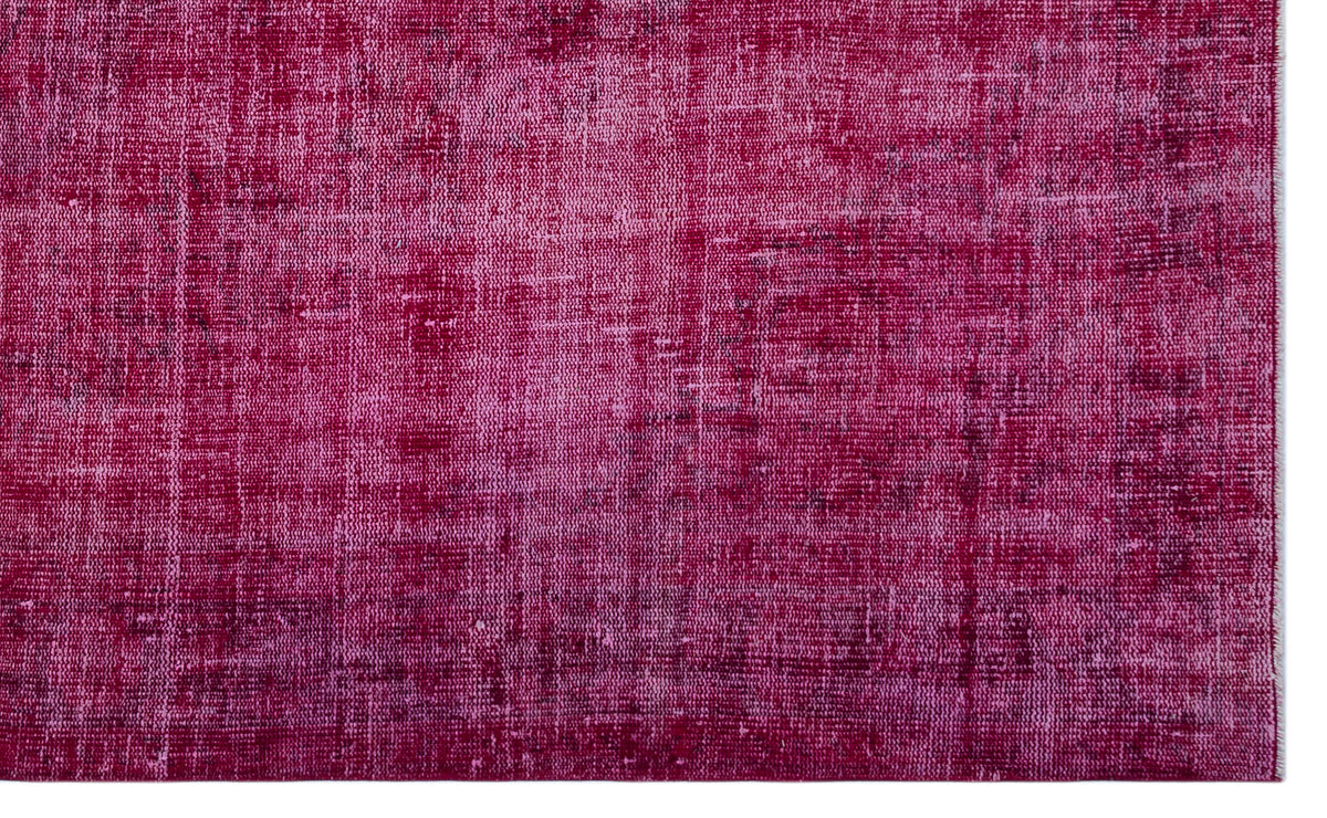 Magenta and dark pink distressed overdyed rug with a faded, textured vintage pattern.