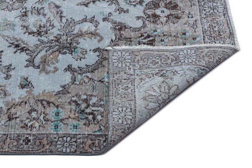 Load image 1 in gallery view. Light blue and brown distressed traditional rug with a floral medallion pattern, shown with a corner folded over.