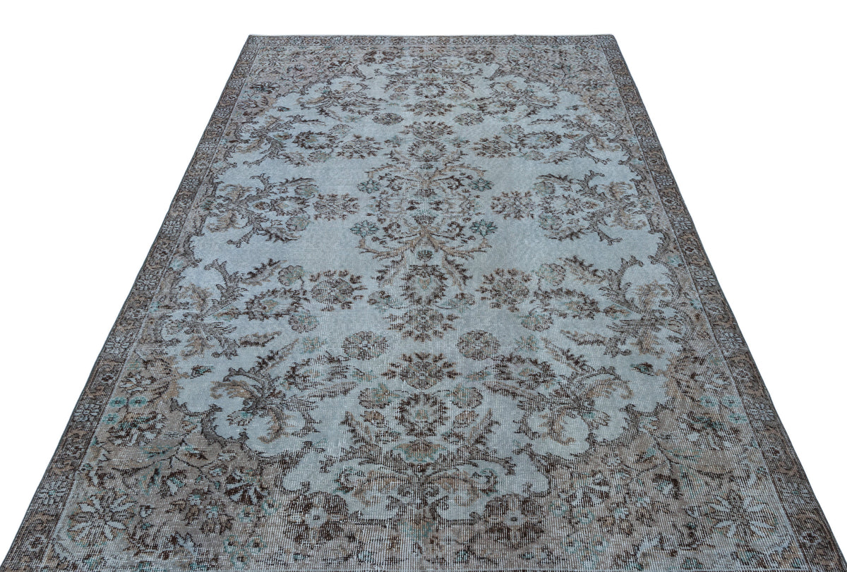 Light blue and brown vintage-style rug with a distressed floral medallion pattern on a white background.