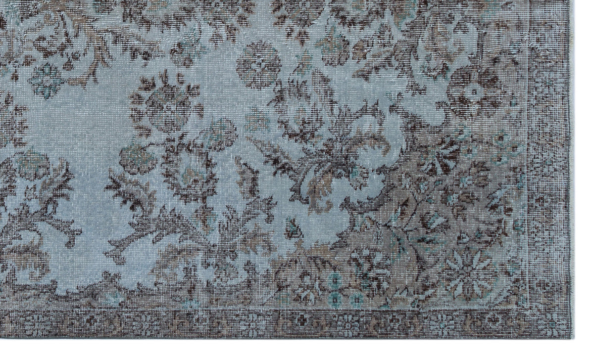 Light blue and brown distressed rug with a traditional floral medallion pattern and a detailed border.