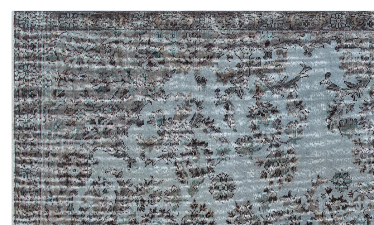 Light blue and brown traditional rug with a distressed floral medallion pattern and a detailed border.