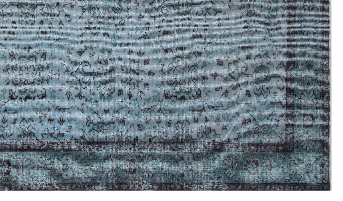 Distressed light blue and charcoal grey rug with a traditional floral medallion pattern and a detailed border.