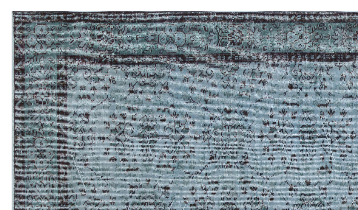 Teal and charcoal distressed rug with a traditional floral medallion pattern and a decorative border.
