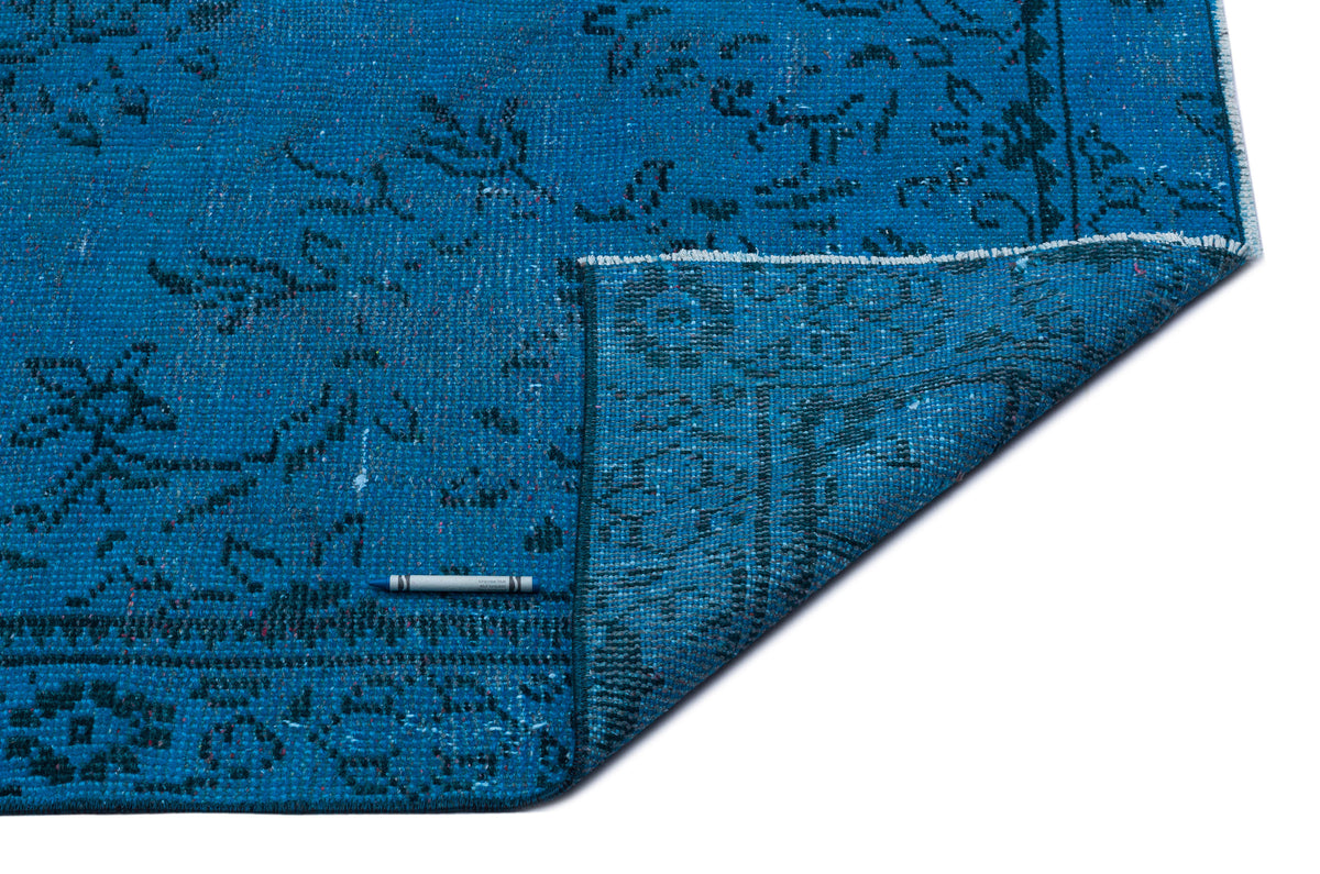 Turquoise blue rug with a distressed traditional floral pattern and a folded corner, isolated on a white background.
