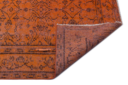 Load image 1 in gallery view. Burnt orange rug with a dark brown distressed floral pattern and a folded corner showing the woven backing.
