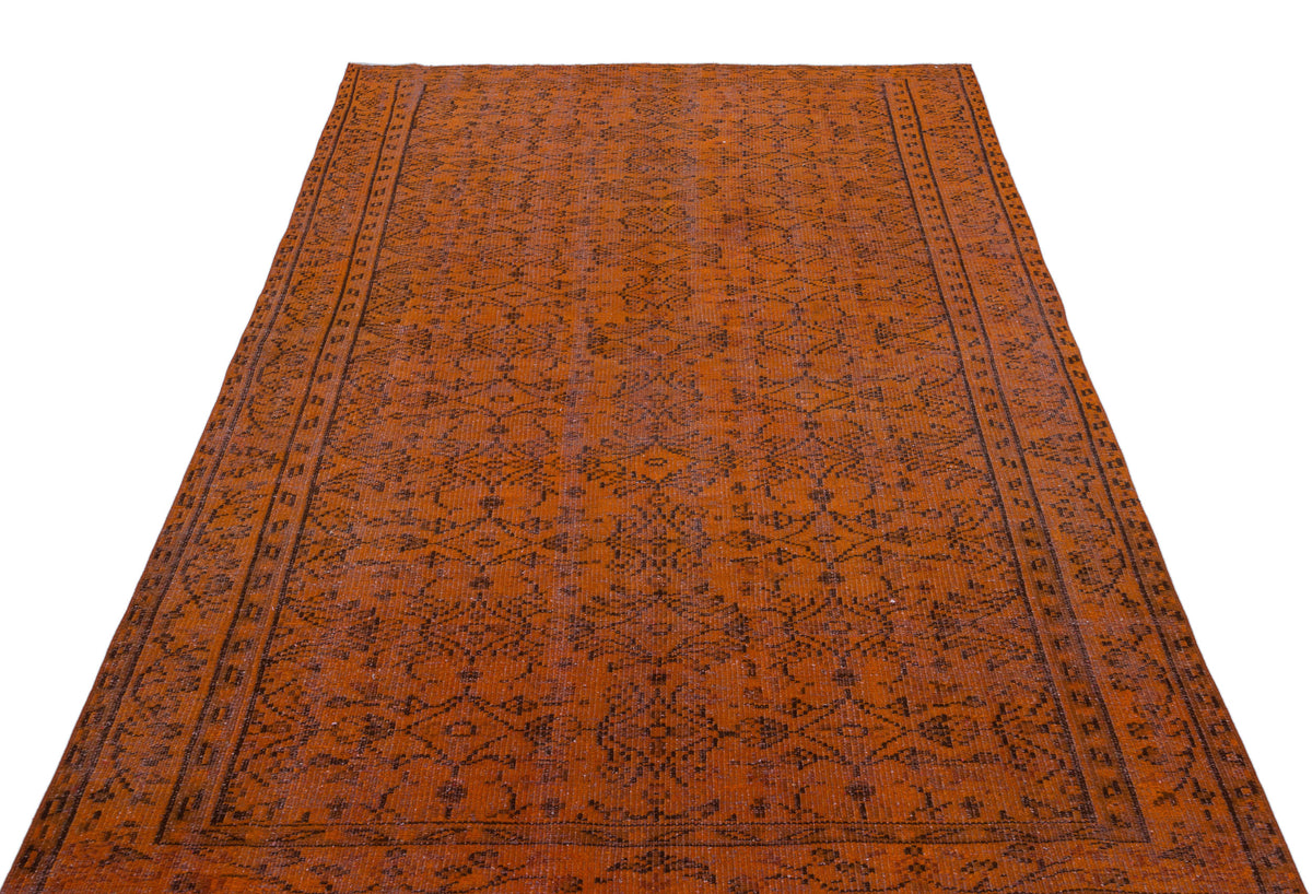 Burnt orange rug with a dark brown traditional geometric medallion pattern and a detailed border.