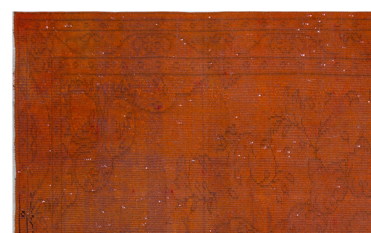 Burnt orange vintage-style rug with a faint, distressed traditional floral pattern and white wear marks.