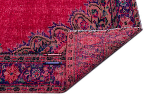 Load image 1 in gallery view. Fuchsia vintage-style rug with a dark floral border and a folded corner, isolated on a white background.