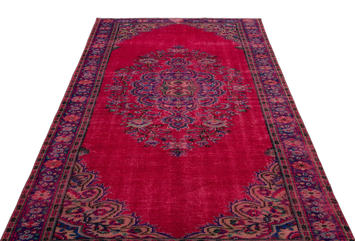 Magenta vintage-style rug with a central floral medallion and ornate border in blue and green tones.