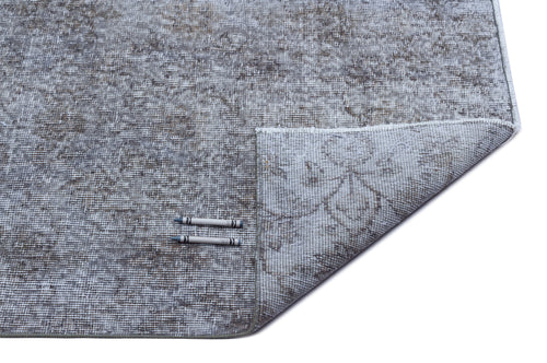 Load image 1 in gallery view. Grey and taupe distressed rug with a faded floral medallion pattern, shown with a corner folded over on white background.