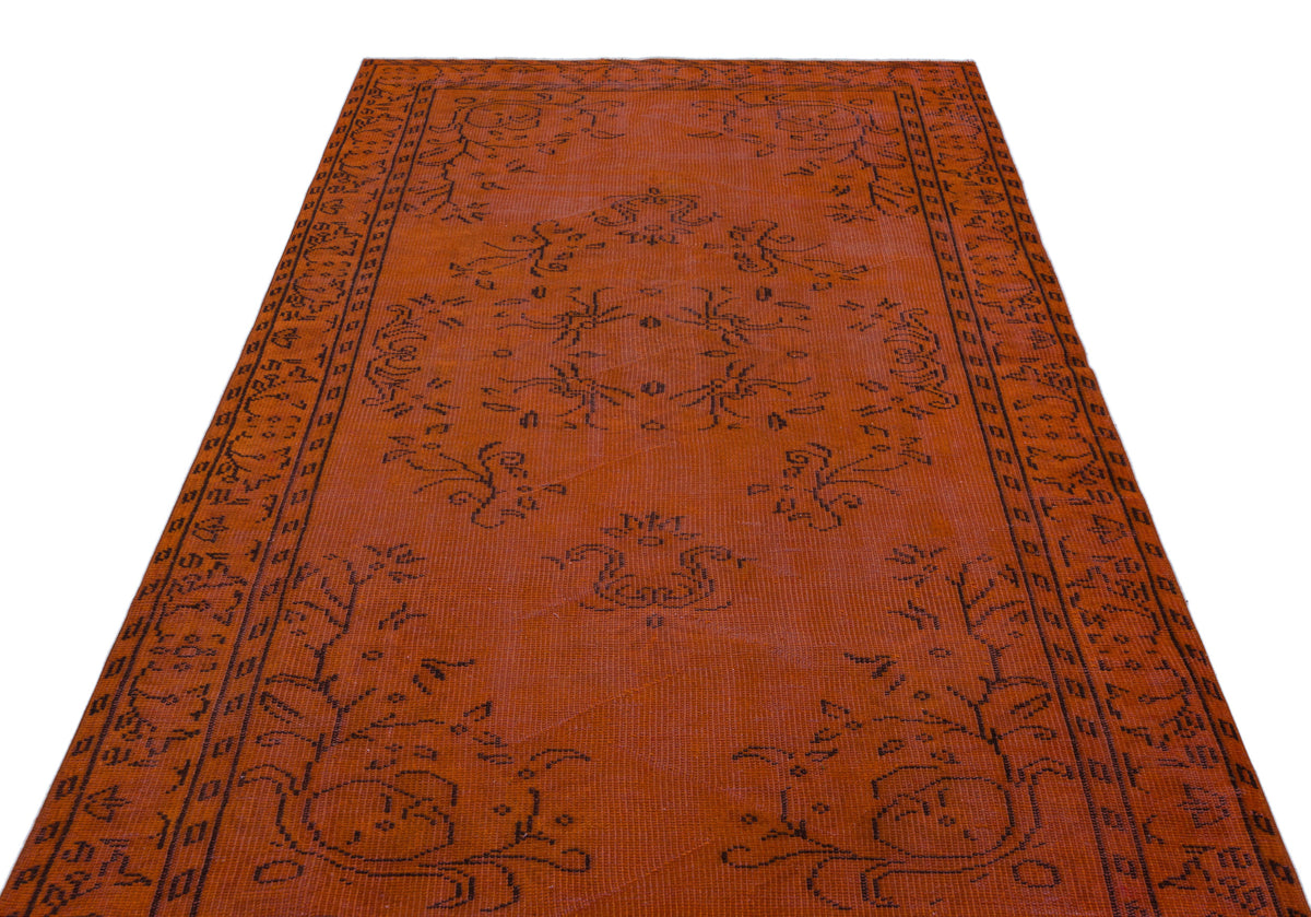 Rust-colored rug with a black linear floral medallion and border pattern on a white background.